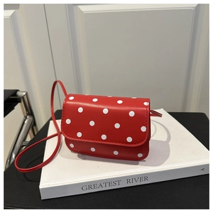 Détail d'un mini sac bandoulière rouge à pois avec lanière en cuir sur fond élégant