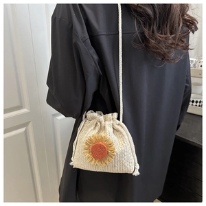 Detail of hand-woven straw bucket bag with sunflower accent and drawstring closure