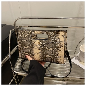 Detailed view of snakeskin pattern envelope bag featuring a metal M logo and hollow handle
