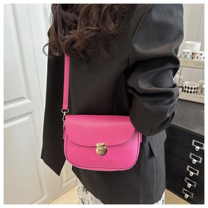 Detail of rose red lychee leather saddle bag with golden push-lock worn by a model