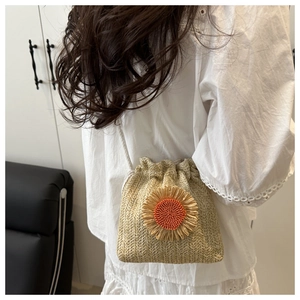 Detail of a straw bucket bag featuring a vibrant sunflower and drawstring closure
