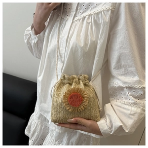 Detail of woven straw bucket bag featuring a beaded sunflower and drawstring closure