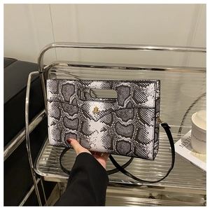 Detail of black and white snakeskin pattern bag with golden buckle and hollow handle