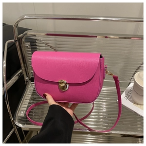 Detail of hot pink litchi texture leather handbag with golden metal lock closure