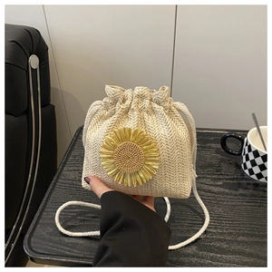 Detail of beige straw bucket bag with a large yellow sunflower and drawstring closure