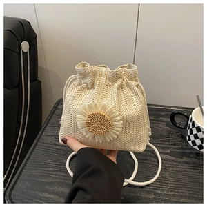 Detail of handwoven straw bucket bag with a 3D daisy flower and drawstring closure
