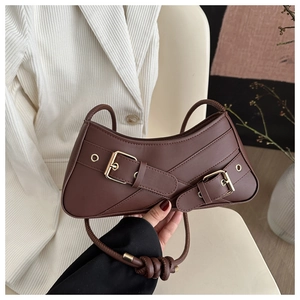 Detailed close-up of dark brown crescent bag with gold buckles and knotted shoulder strap