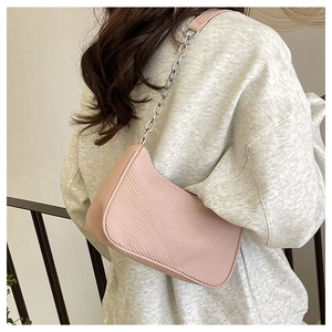 Detail of pink crescent shoulder bag with silver chain strap worn over grey hoodie