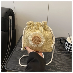 Detailed close-up of straw bucket bag featuring a large white 3D daisy and cotton rope strap