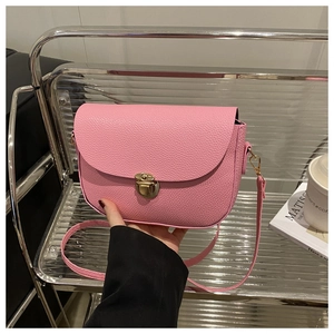 Detail of pink lychee leather handbag featuring a golden push-lock and metal hook strap