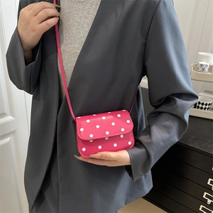 Petit sac bandoulière rose à pois porté avec un blazer gris pour un style moderne chic