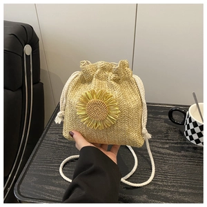 Detail of hand-woven straw bucket bag with sunflower applique and cotton drawstring