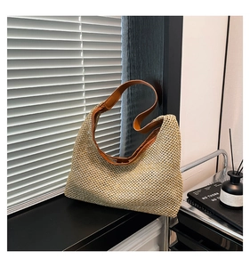 Détail du sac hobo en paille tressée beige avec finitions et bandoulière en cuir brun
