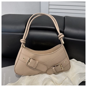 Detail of beige faux leather shoulder bag with decorative gold buckles and knot handle