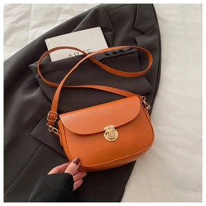 Detail of orange pebble-grain shoulder bag with gold metal buckle and semi-circle flap