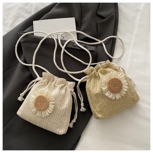 Detail of straw bucket bags with sunflower decor in cream and khaki with drawstring closure