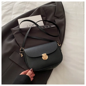 Detail of the black pebble leather texture and golden semi-circle lock on the shoulder bag