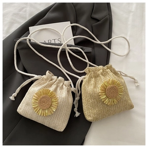 Close-up of woven straw bucket bag with 3D sunflower detail and drawstring strap