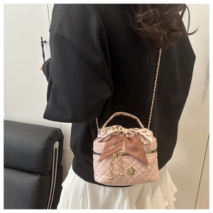 Detailed view of mini pink quilted bag with bow and chain strap on a model