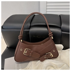 Detailed view of deep brown baguette bag with golden buckle straps and sleek top handle