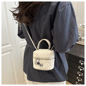 Détail du sac bandoulière matelassé blanc avec chaîne argentée et breloques en métal