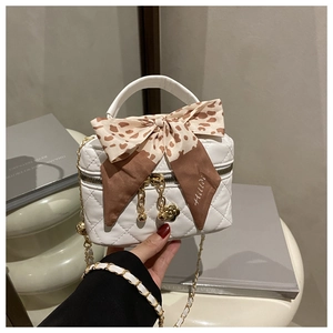 Detail of white quilted mini handbag featuring a leopard bow and golden flower charm
