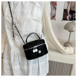 Détail du sac boîte en velours matelassé avec pendentif camélia et chaîne argent