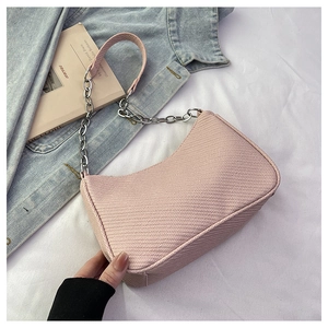 Gros plan du sac sous l'aisselle rose avec texture tissée et chaîne argentée