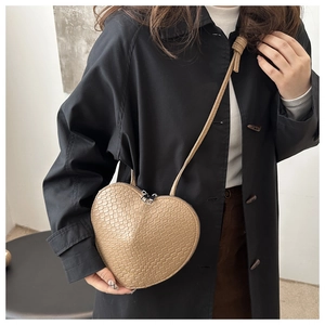 Detail view of heart-shaped crossbody bag featuring textured crocodile embossed leather