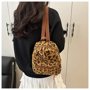 Detailed back view of a mini leopard print corduroy backpack on model for size reference
