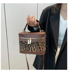 Détail d'un sac boîte imprimé léopard avec zips dorés et poignée en cuir marron
