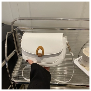 Détail du sac de selle blanc avec fermoir en fer à cheval doré et texture lisse élégante