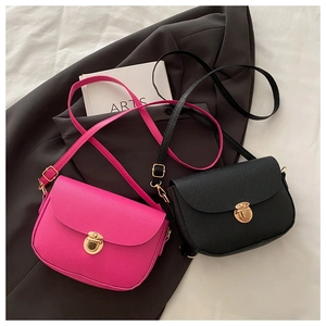 Detail of lychee pattern leather and metallic buckle on magenta and black saddle bags