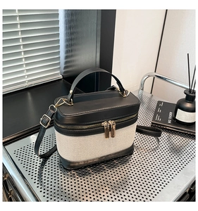 Détails du sac boîte à bandoulière en toile et cuir posé sur une étagère moderne