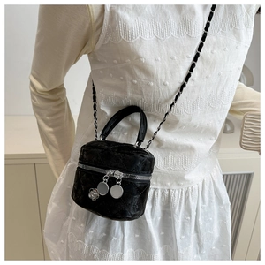 Détail du mini sac matelassé en velours noir avec breloque fleur et bandoulière chaîne