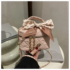 Detail of pink quilted mini bag with a large printed bow and gold camellia hardware