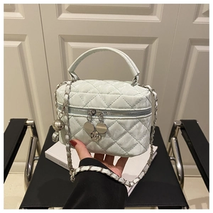Détail du sac seau matelassé vert clair avec bandoulière chaîne et breloques en métal