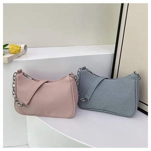Détail de sacs à chaîne minimalistes en tissu texturé rose et gris-bleu avec accents argentés