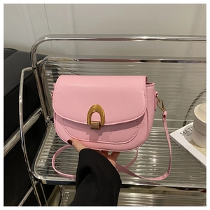 Vue détaillée du sac besace rose avec boucle fer à cheval dorée et cuir synthétique lisse