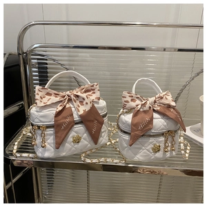Detail of white quilted bucket bags with camellia metal logo and leopard bow ribbons