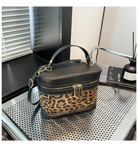 Détail du sac à main léopard avec fermetures dorées et poignée en cuir noir élégante