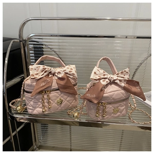 Detail of pink quilted bucket bag with gold camellia clasp and leopard silk scarf