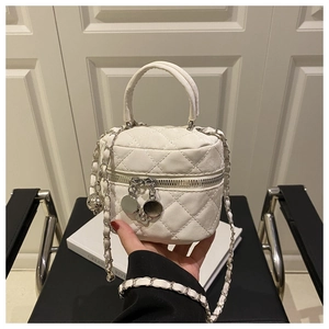 Détail d'un sac à main blanc matelassé avec chaîne en métal et breloques florales