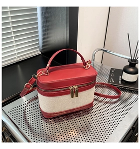 Détail d'un sac à main en toile rouge et beige avec accessoires dorés sur étagère