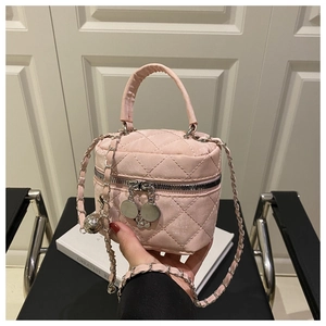 Détail d'un mini sac à main rose matelassé avec pendentif camélia et clochette argentée