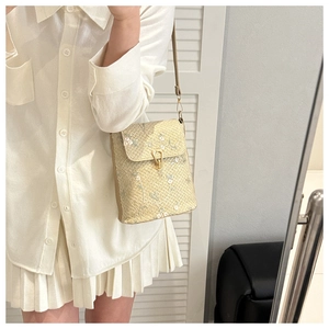 Détail d'un sac en paille beige avec broderie florale délicate et fermoir en métal doré