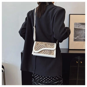 Detail of white leather saddle bag with vintage textured jacquard pattern on shoulder