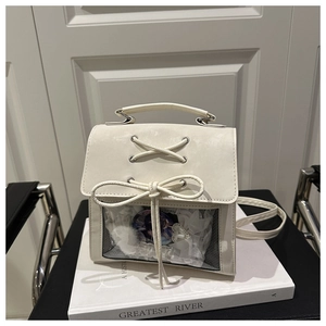 Detailed view of white Ita bag featuring a clear PVC window and elegant lace decoration