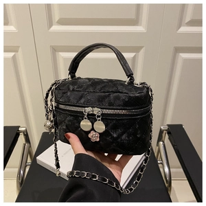 Détail du sac seau matelassé noir avec pendentif camélia et bandoulière en chaîne