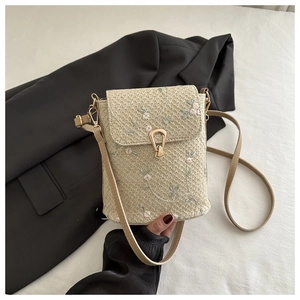 Détail du sac en paille beige avec broderies florales délicates et fermoir en métal rétro